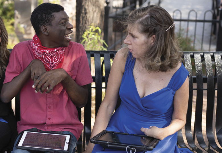 Boy and girl sitting on bench using their speech generating devices