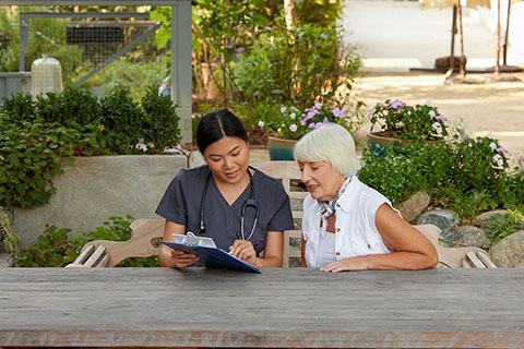 clinical employee looking at clipboard with patient
