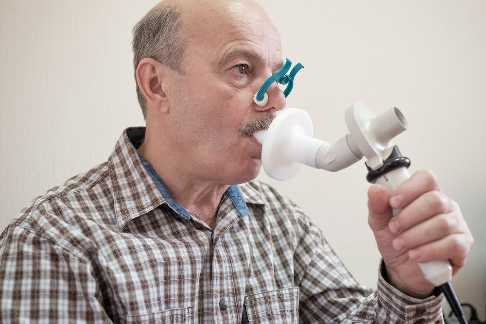 senior man testing breathing function by spirometry