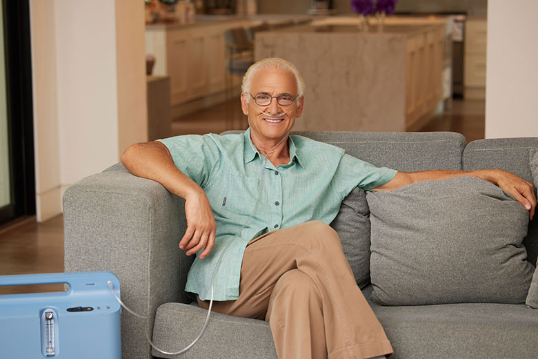 Oxygen WhiteMale SittingOnCouch OxygenConcentrator RespironicsEverflow 5LPM web flip