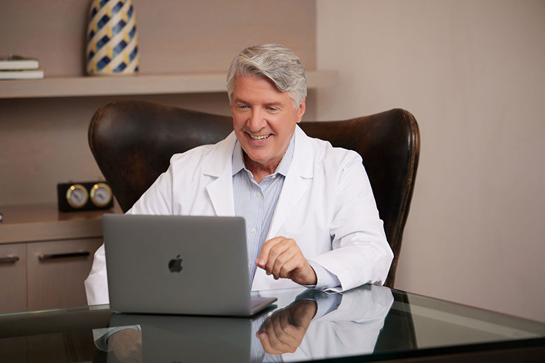 Telehealth WhiteMaleDoctorSmiling TalkingonLaptop web flip