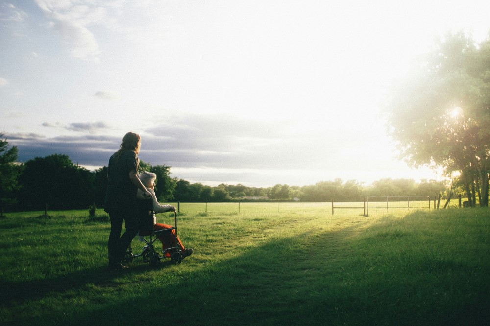 woman pushing another woman in a wheelchair while watching the sun
