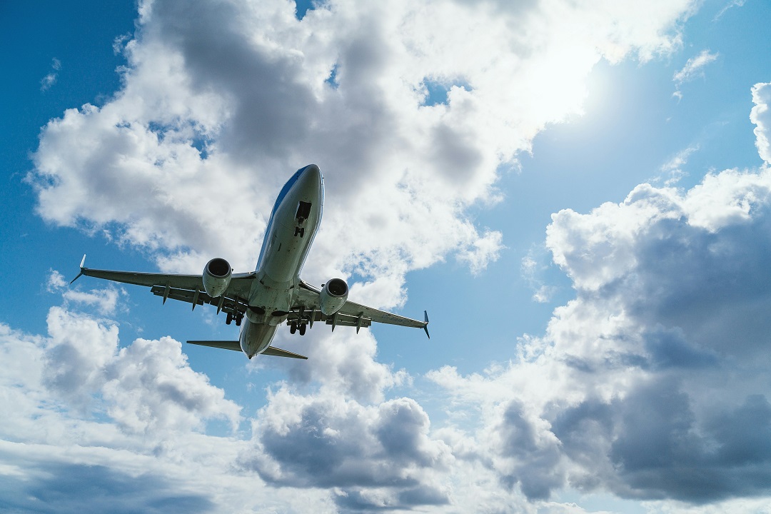 airplane in a blue partially cloudy sky