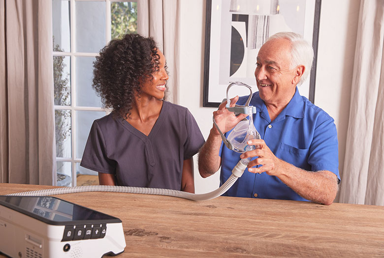 Non Invasive Vent NHV BlackFemaleClinicianWhiteMale SittingAtDiningTable Ventilator Luisa2