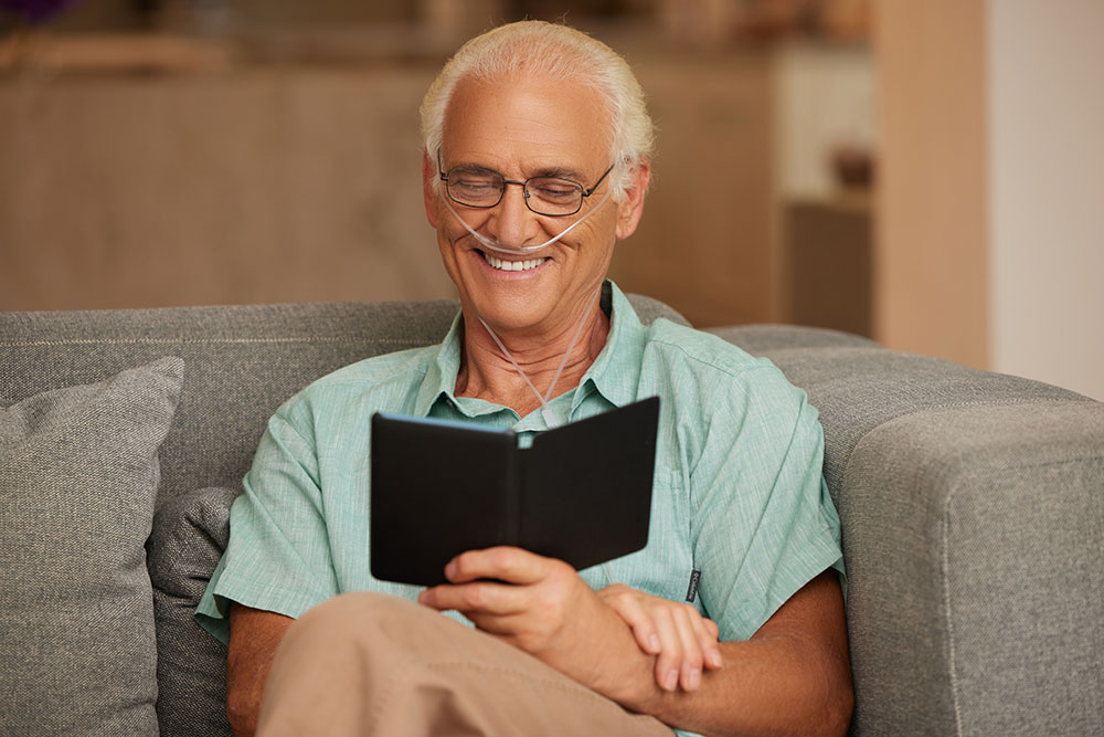 Oxygen White Male Sitting on Couch Reading Nasal Cannula