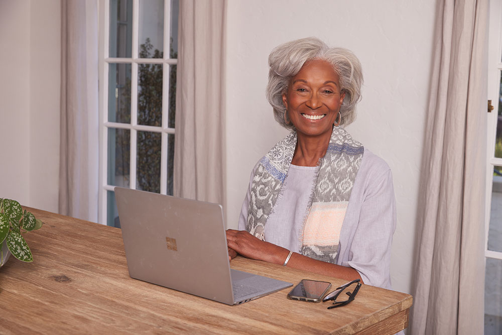 Telehealth Black Older Female Dining Room on Laptop looking at Camera