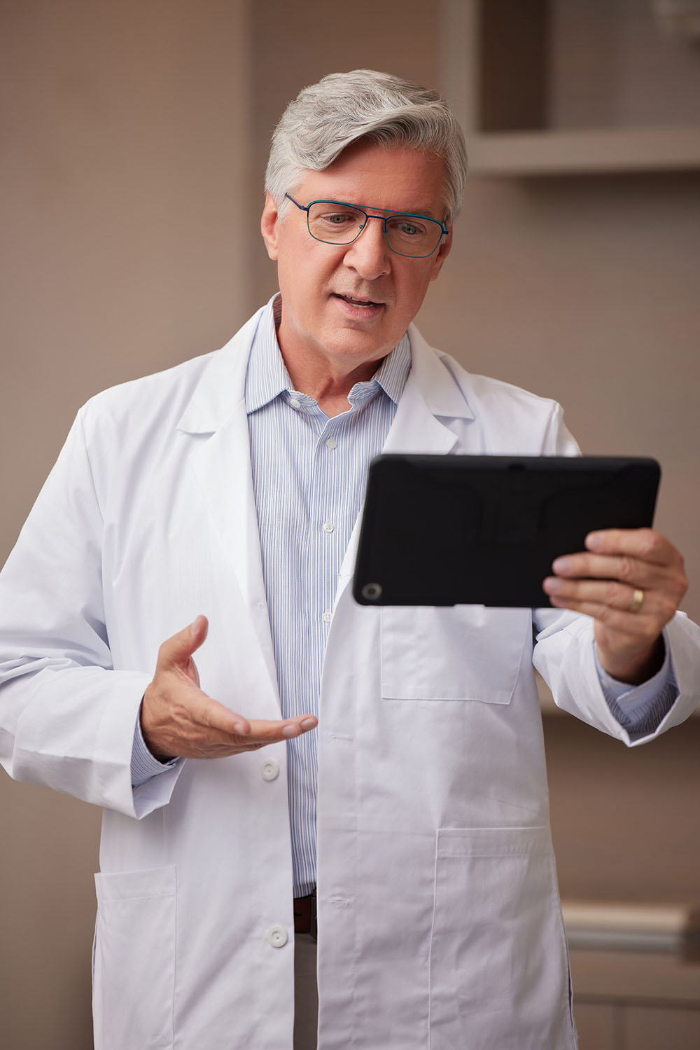 Telehealth White Male Doctor with Glasses Standing Up Talking on Tablet