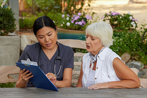 clinical employee looking at clipboard with patient