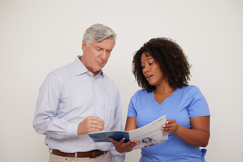 clinical employee looking a booklet with patient