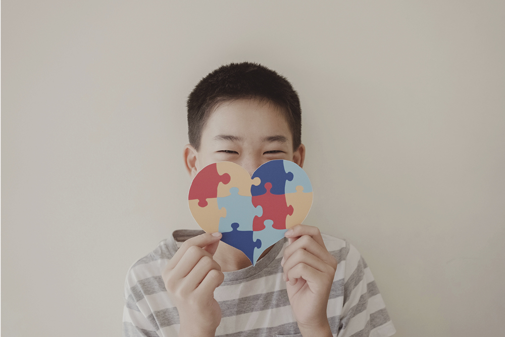 child holding up heart with puzzle shapes on it